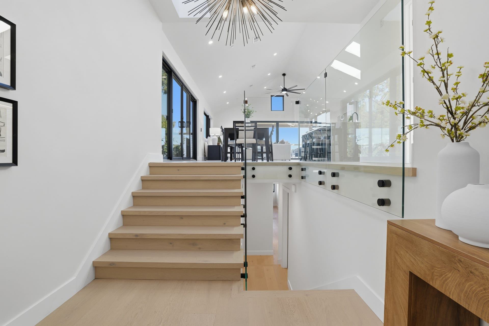 Modern wood staircase with glass railing and open living view