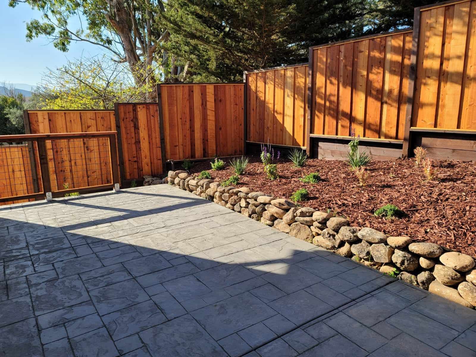 Backyard patio with river rock retaining wall and privacy fence