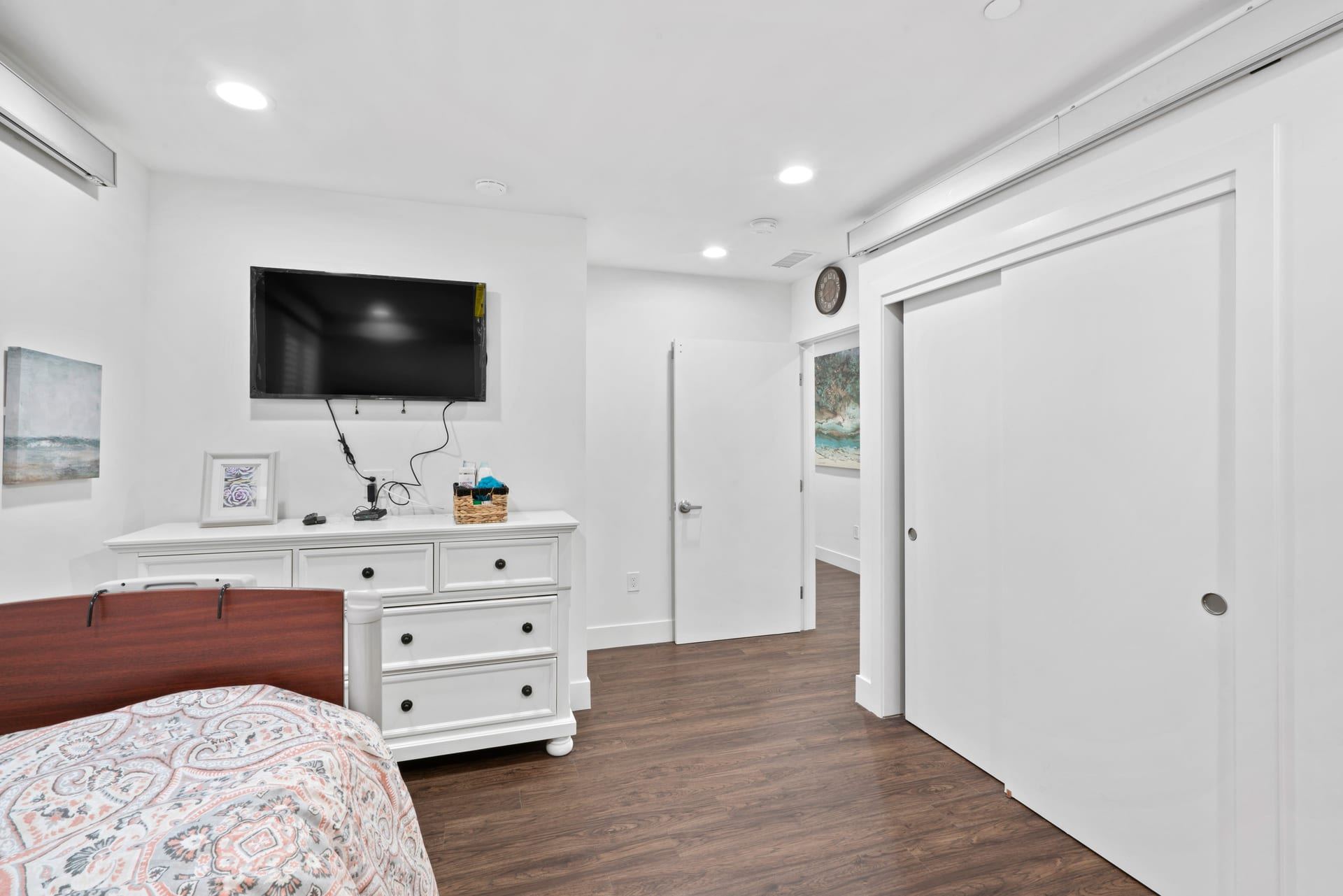 Accessible bedroom with wide sliding doors and dark wood look flooring novato