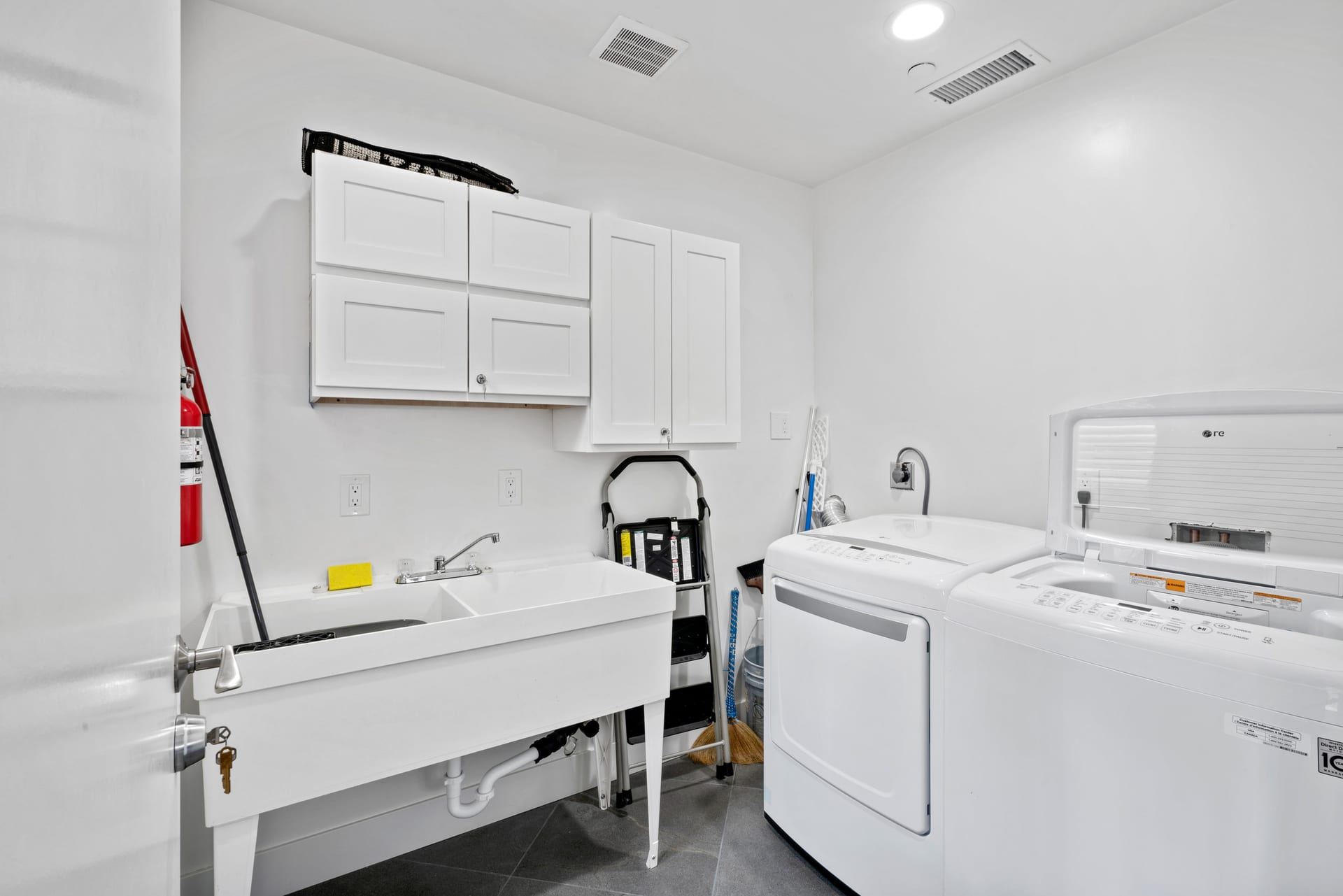 Accessible laundry room with utility sink and white cabinetry novato