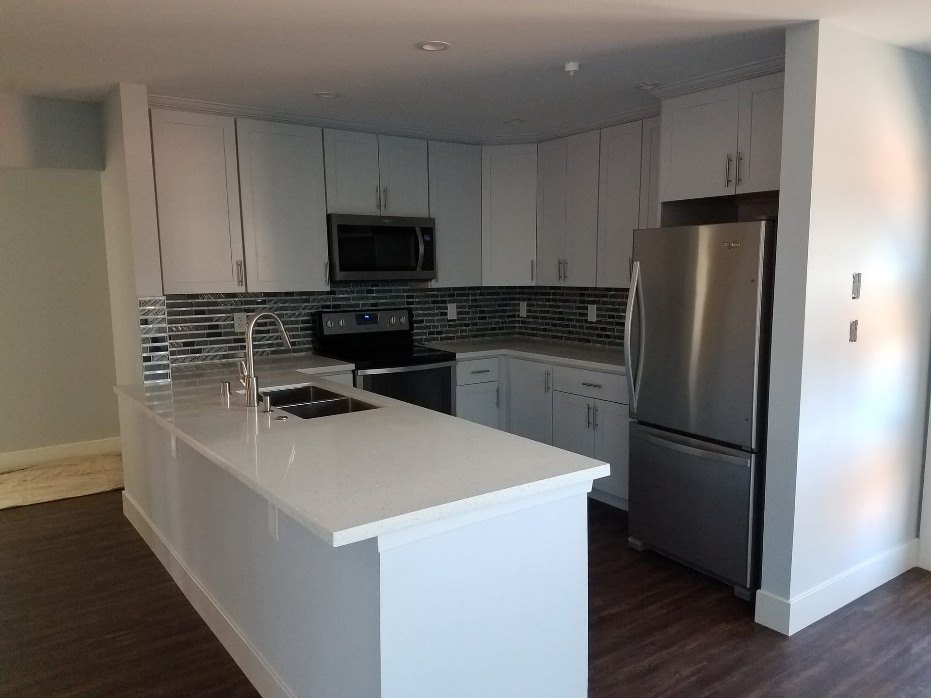 Compact white kitchen with peninsula and mosaic backsplash