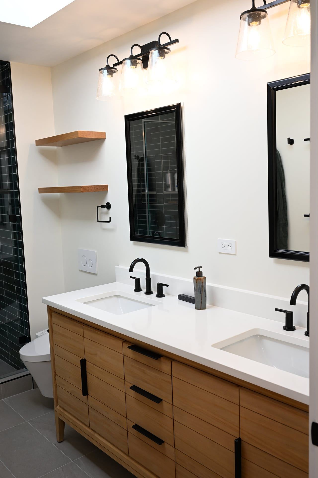 Natural wood double vanity with black fixtures and floating shelves