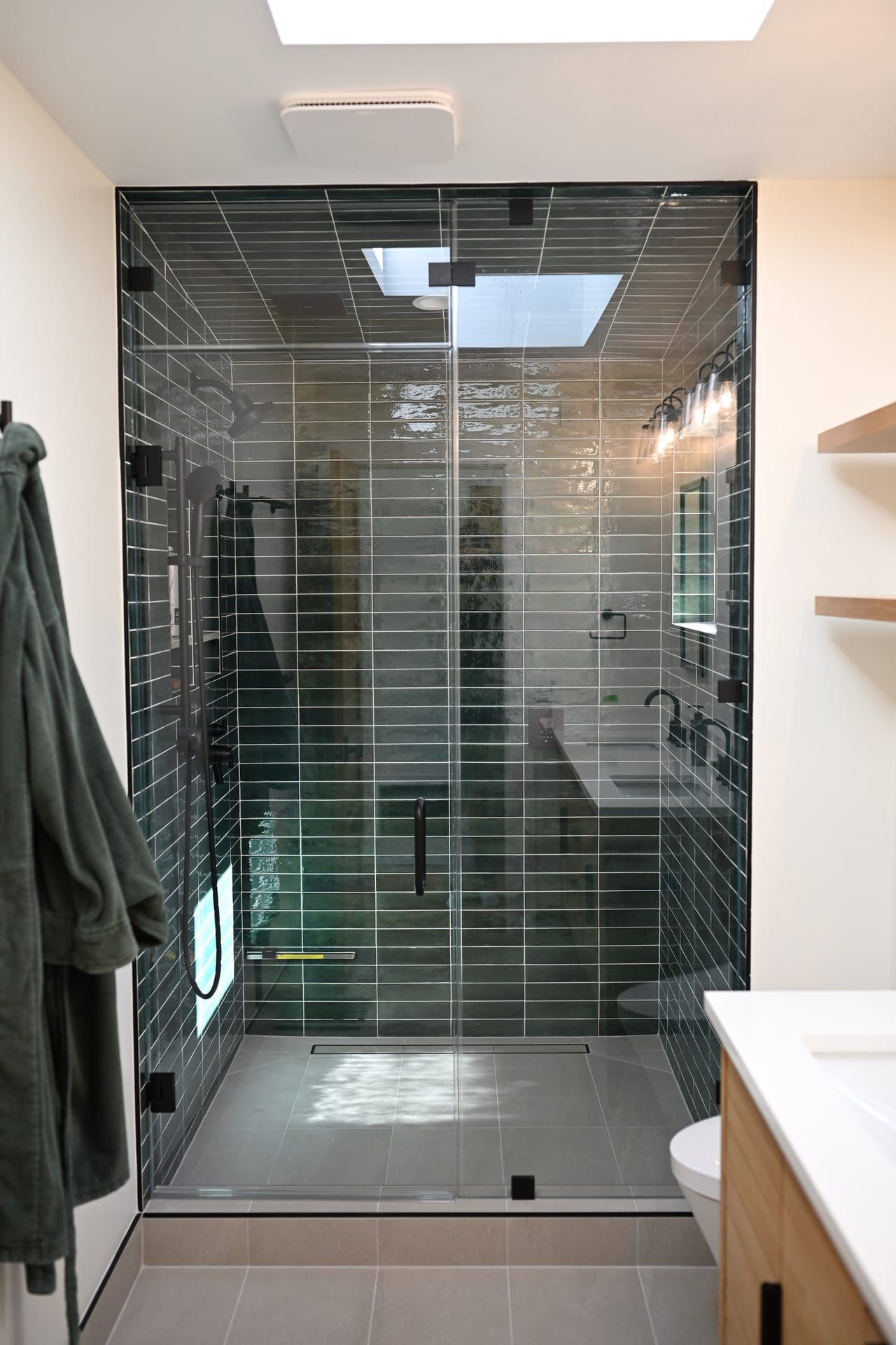 Glossy green tile walk in shower with frameless glass enclosure