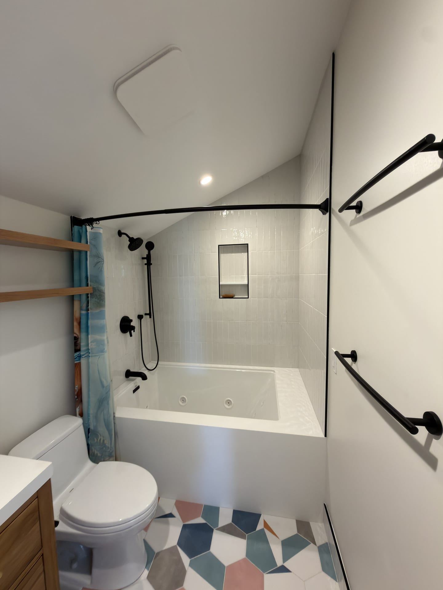 White tub shower bathroom with geometric colorful floor tile