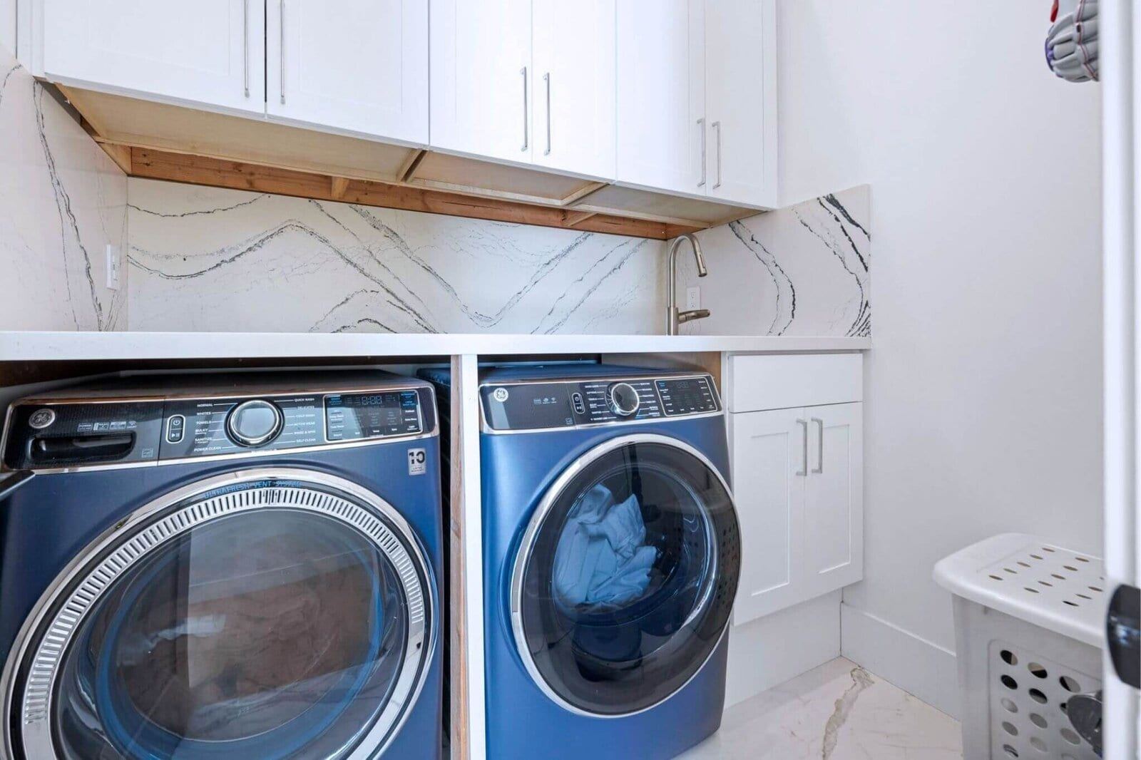 Bright laundry room with marble look backsplash and built in storage