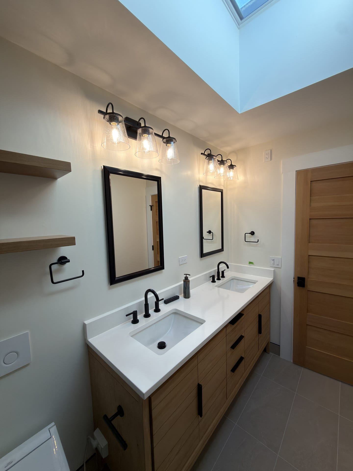 Skylit double vanity bathroom with natural wood cabinetry