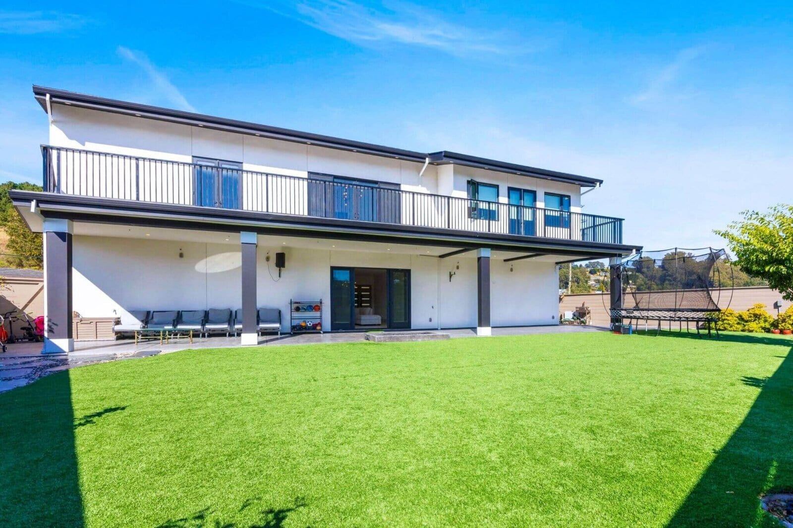 Modern backyard exterior with expansive lawn and covered patio