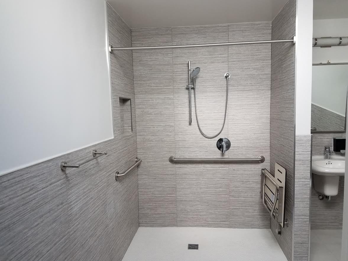 Accessible roll in shower with grab bars and folding seat