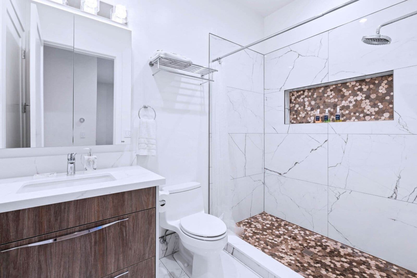 Adu bathroom with marble look tub shower and wood vanity