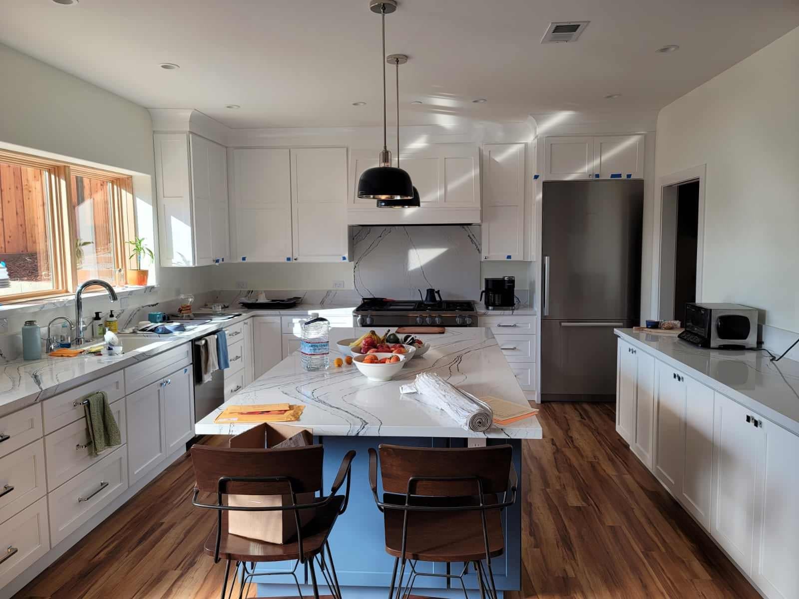 Blue kitchen island with white shaker cabinets and veined backsplash daly city