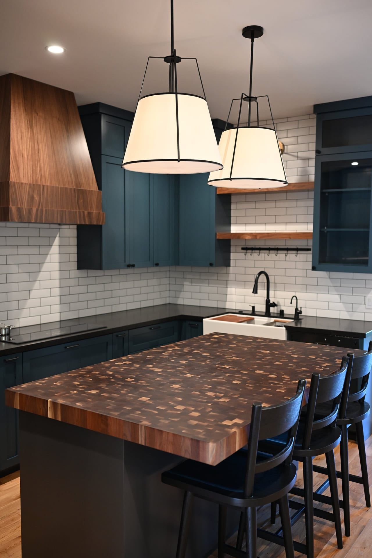 Large wood kitchen island with lantern pendants and teal cabinetry