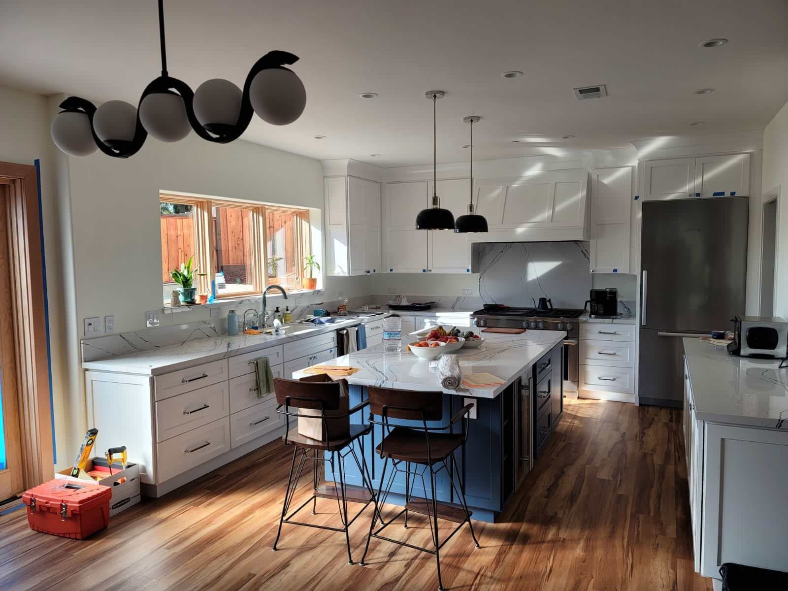 White transitional kitchen with a blue island and statement lighting in Daly City