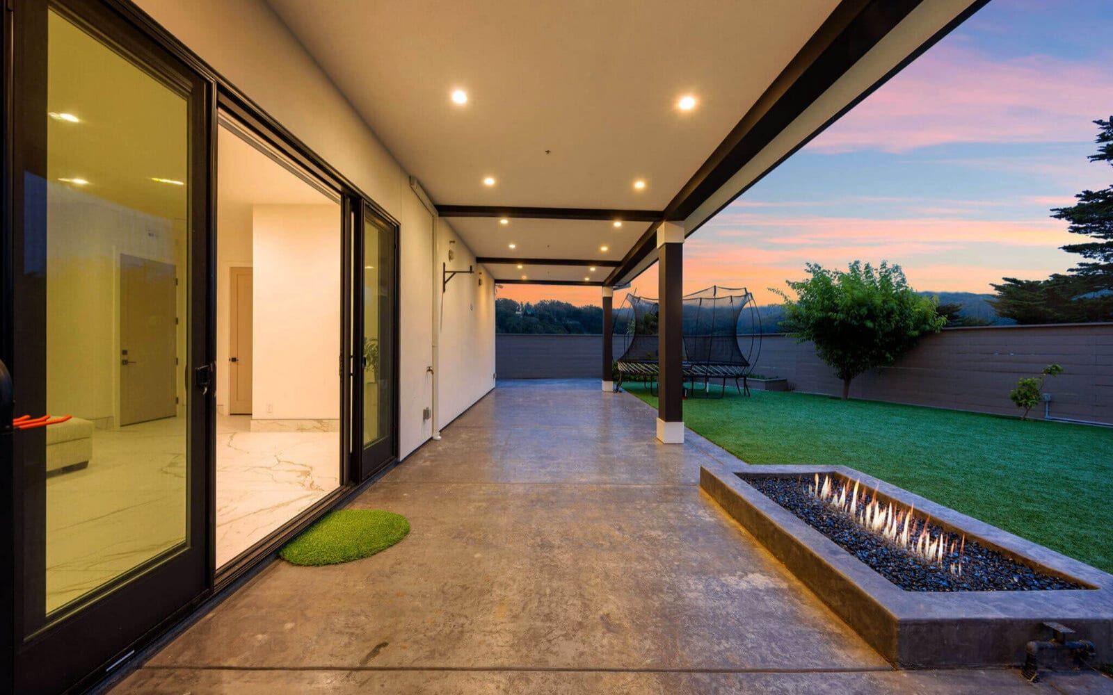 Covered outdoor patio with a linear fire pit at sunset in Pacifica