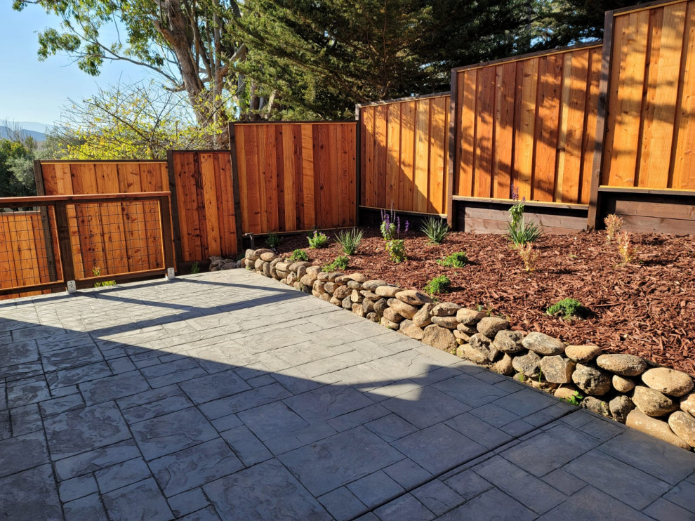 Stamped-Concrete Backyard Patio with Tiered Privacy Fence