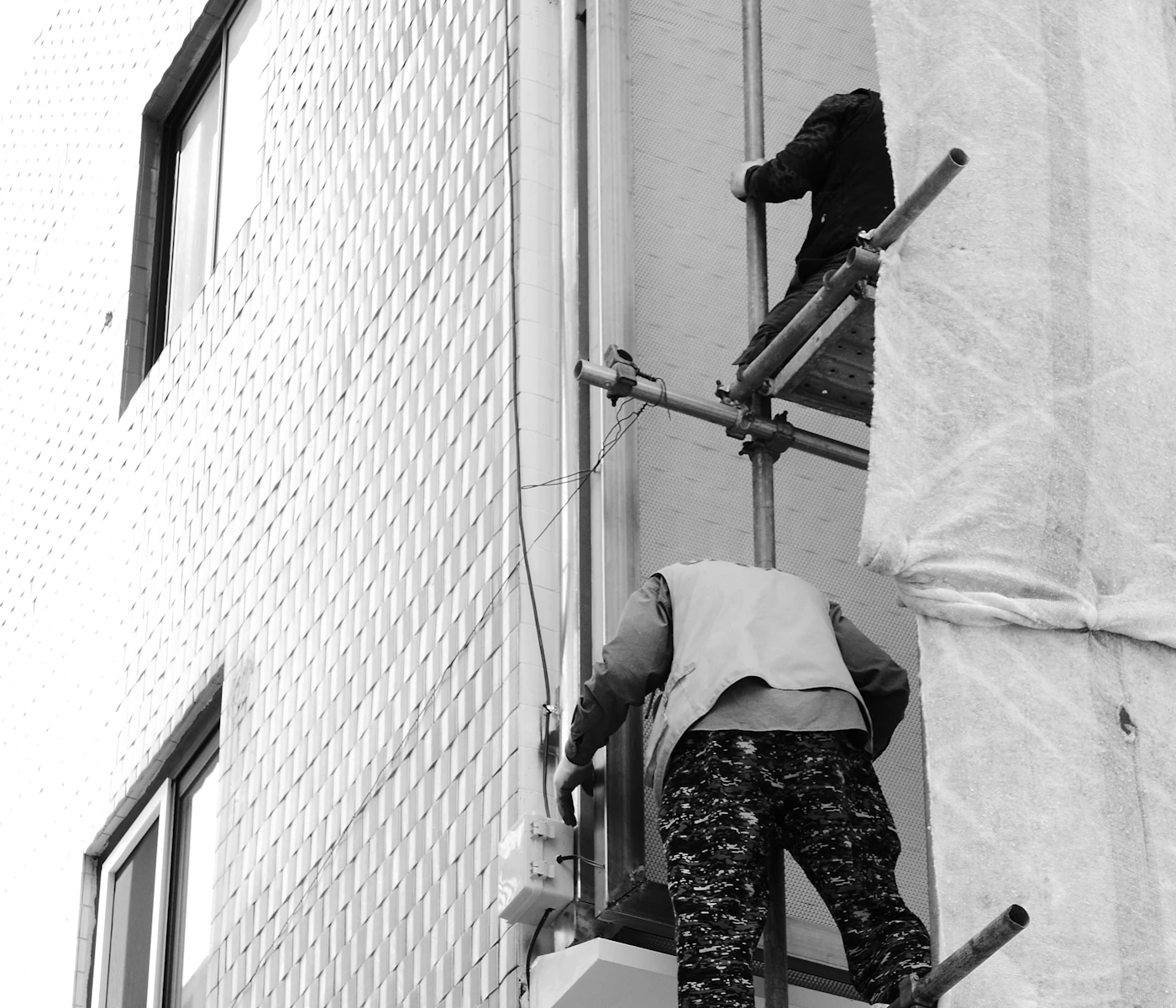 Workers installing scaffolding on a building exterior